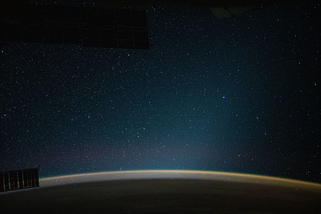 An atmospheric glow blankets Earth beneath a starry night sky